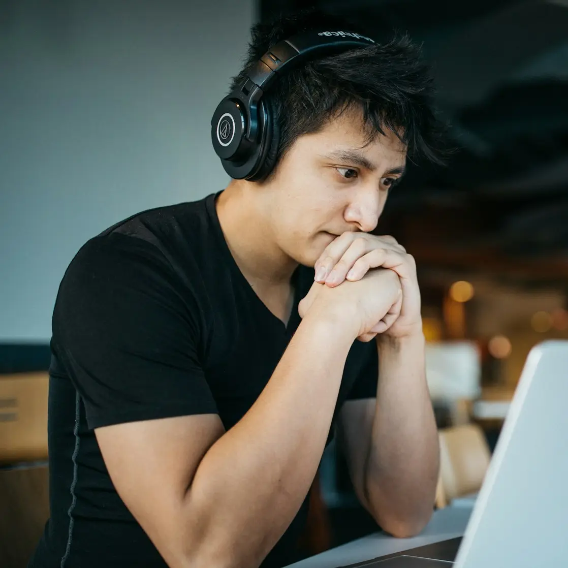 man wearing headphones while sitting on chair in front of MacBook