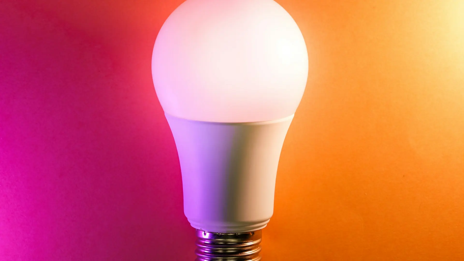 a white light bulb on an orange and pink background