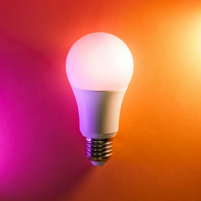 a white light bulb on an orange and pink background