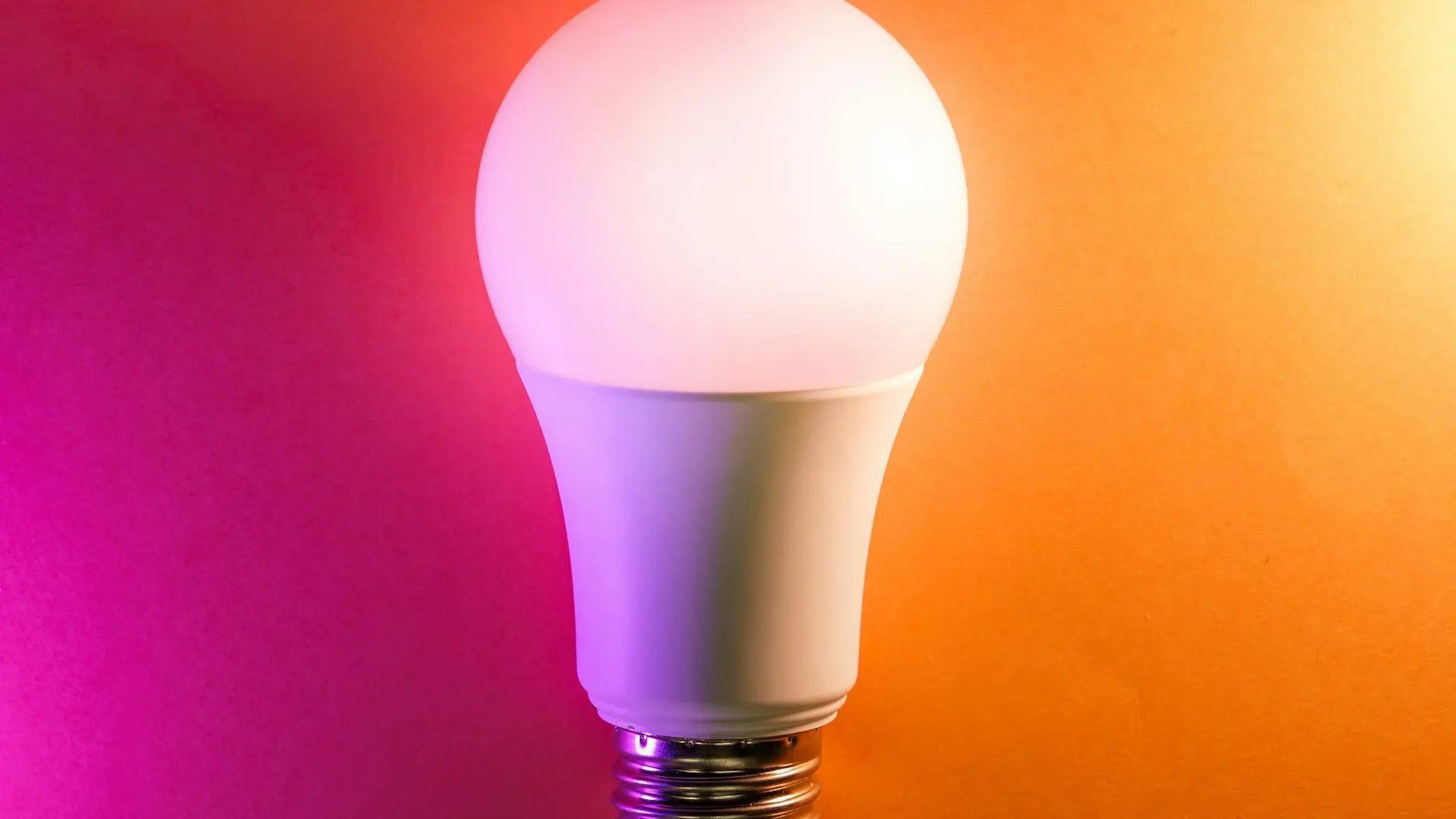 a white light bulb on an orange and pink background